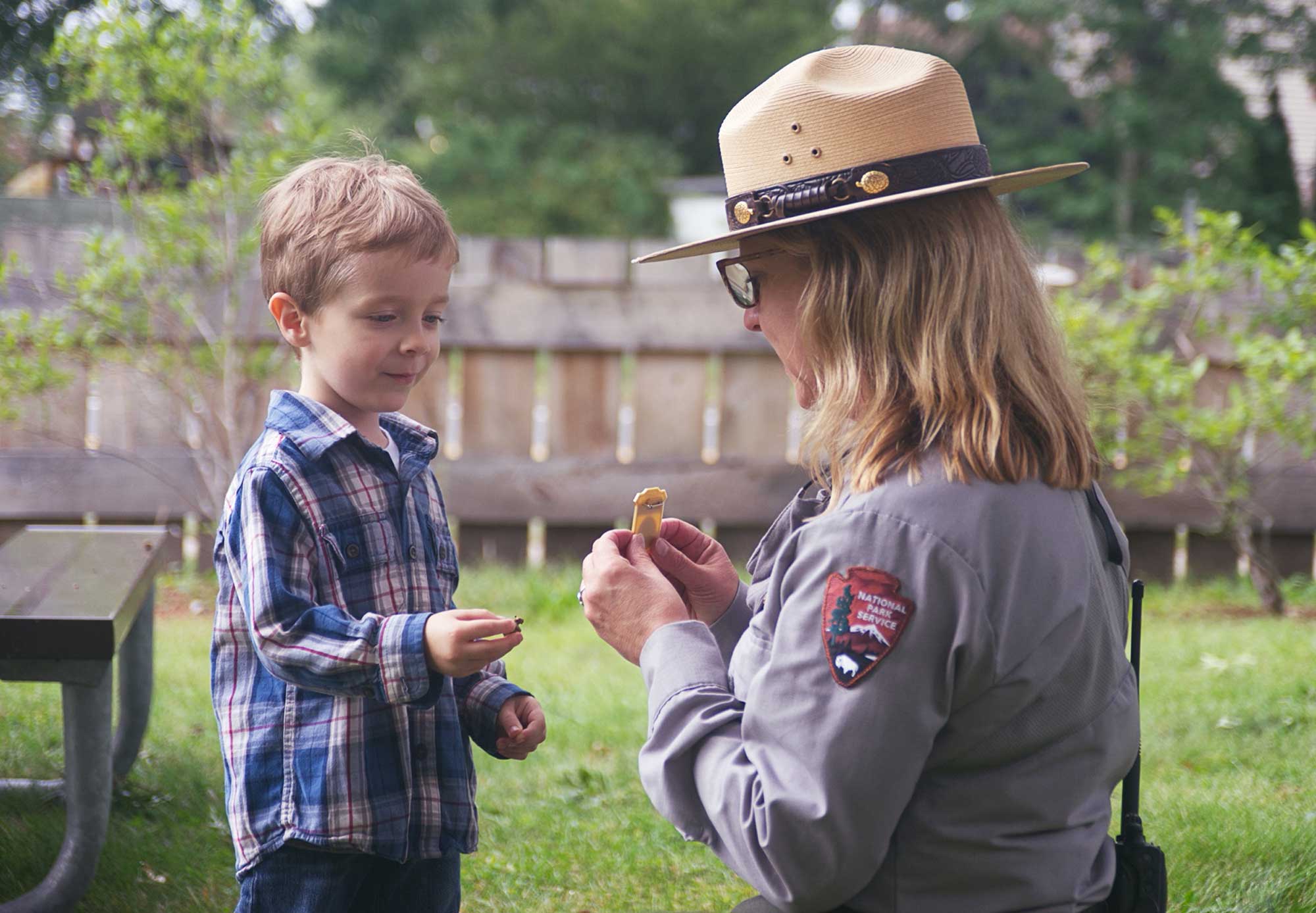 park ranger giving junior ranger badge to young boy